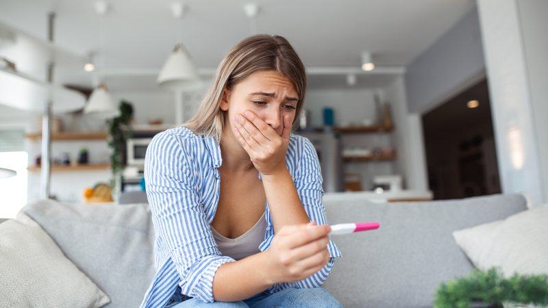 Woman looking worried at a negative pregnancy test while waiting for a late period
