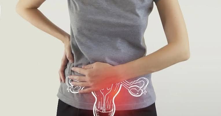 Woman holding her lower abdomen with an illustration of the uterus showing pelvic discomfort