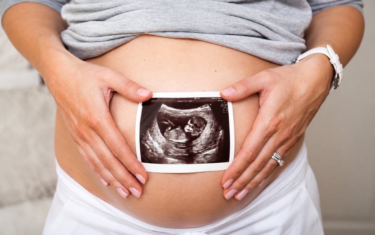 Pregnant woman holding an ultrasound photo over her belly
